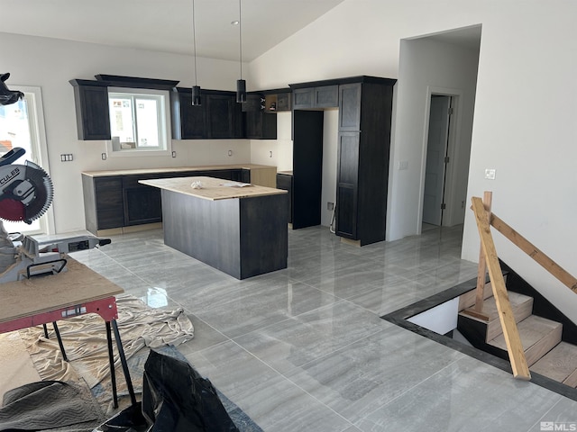 kitchen featuring a center island, pendant lighting, marble finish floor, high vaulted ceiling, and dark cabinets