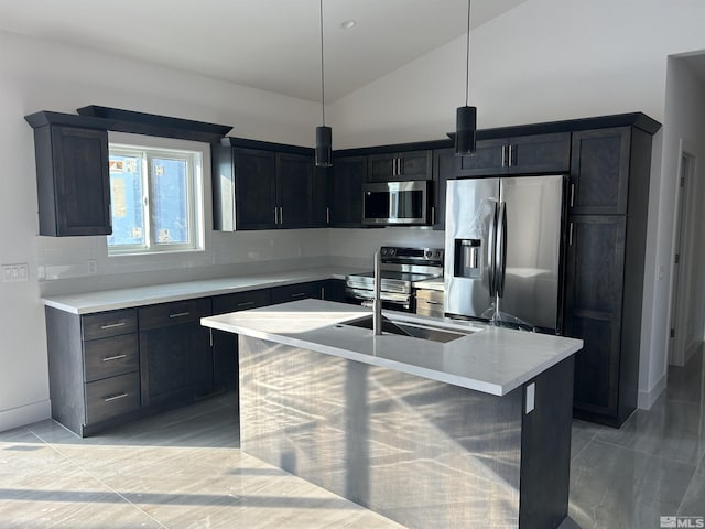 kitchen featuring a kitchen island with sink, stainless steel appliances, hanging light fixtures, vaulted ceiling, and light countertops