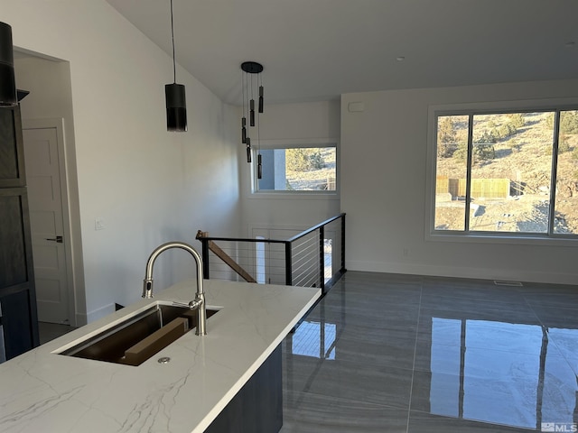 kitchen with visible vents, dark tile patterned floors, a sink, baseboards, and light stone countertops