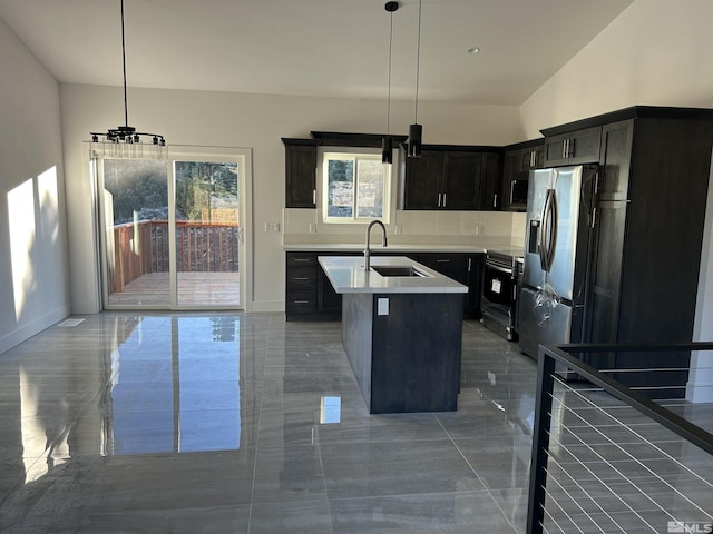 kitchen featuring an island with sink, a sink, hanging light fixtures, light countertops, and stainless steel appliances