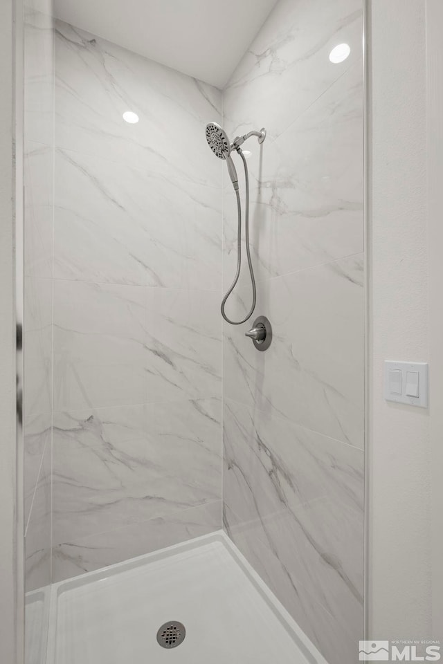 bathroom featuring a marble finish shower