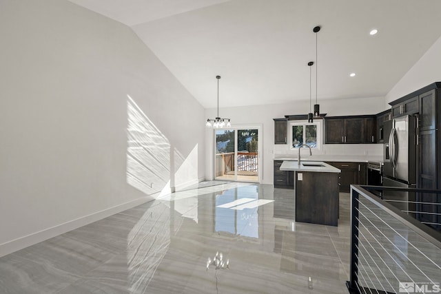 kitchen featuring pendant lighting, a center island with sink, stainless steel fridge, light countertops, and baseboards