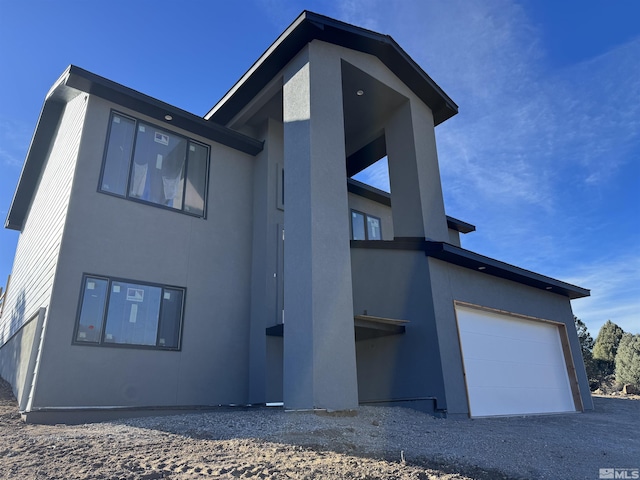 rear view of property with a garage and stucco siding