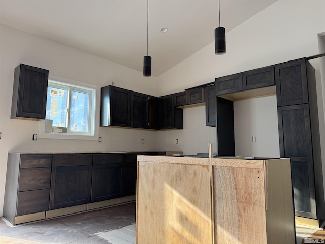 kitchen featuring decorative light fixtures, dark cabinets, and vaulted ceiling