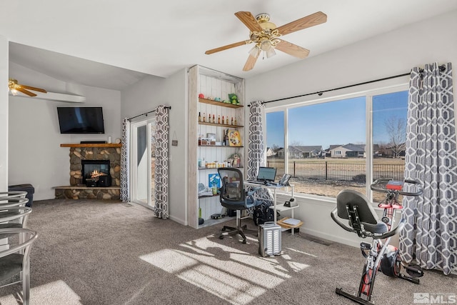 exercise area featuring carpet, ceiling fan, and a fireplace