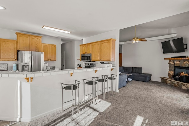 kitchen with tile countertops, light carpet, a breakfast bar, and stainless steel appliances