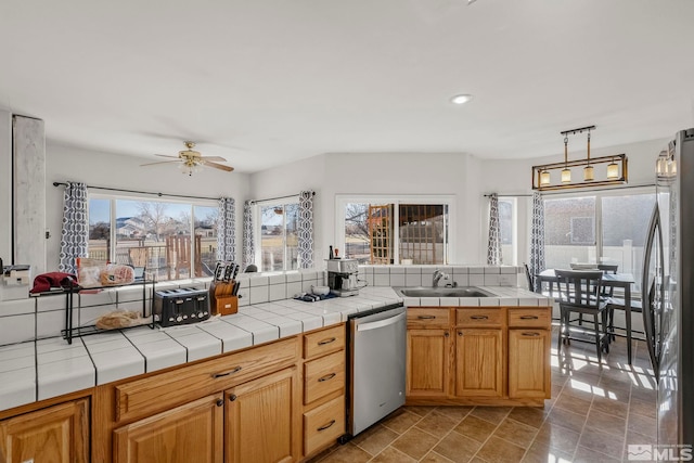 kitchen with appliances with stainless steel finishes, tile countertops, and a healthy amount of sunlight