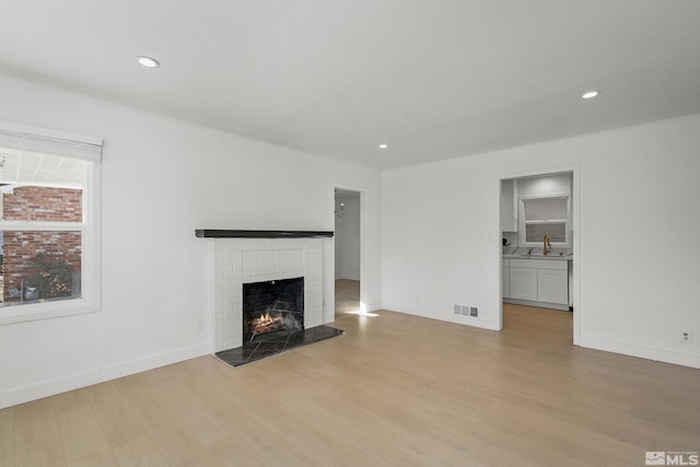 unfurnished living room featuring a fireplace, light hardwood / wood-style floors, and ornamental molding