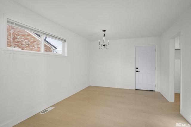 unfurnished room featuring light hardwood / wood-style floors and a chandelier