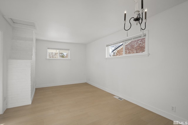 spare room featuring light hardwood / wood-style floors and a chandelier