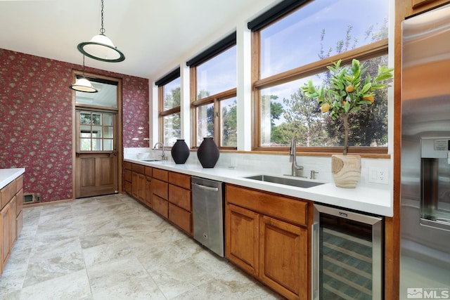 kitchen with wine cooler, sink, decorative light fixtures, and appliances with stainless steel finishes