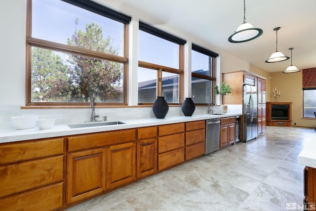 kitchen with hanging light fixtures, appliances with stainless steel finishes, a wealth of natural light, and sink