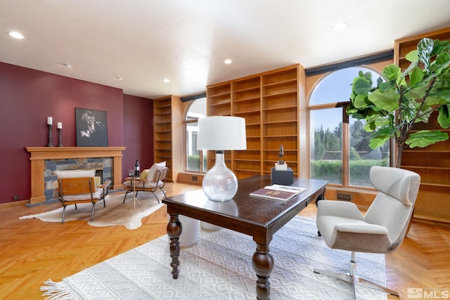 home office with a stone fireplace and light parquet floors