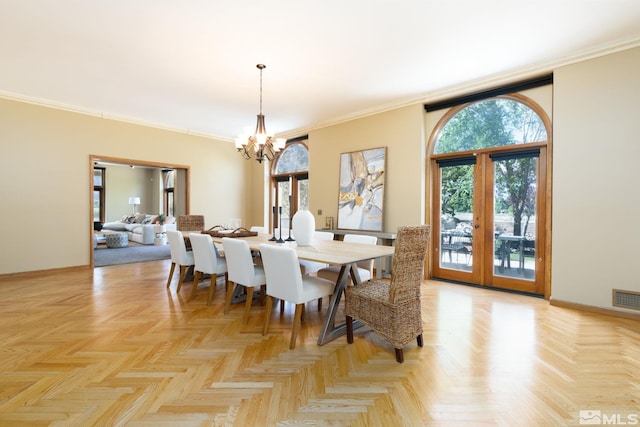 dining space with french doors, light parquet flooring, an inviting chandelier, and crown molding