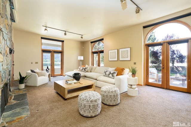 carpeted living room with french doors, rail lighting, and a wealth of natural light