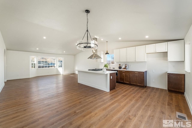 kitchen featuring hardwood / wood-style floors, decorative light fixtures, a kitchen island, white cabinetry, and a chandelier