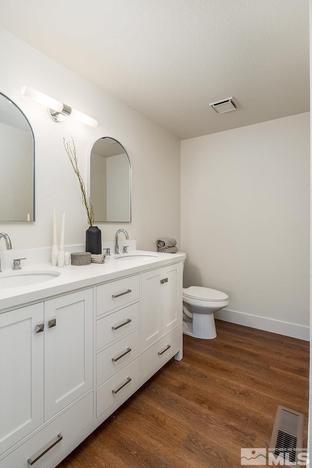 bathroom featuring hardwood / wood-style floors, vanity, toilet, and a textured ceiling