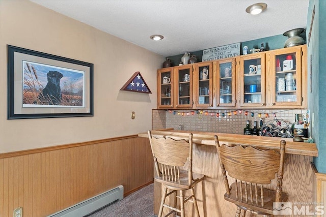 bar with carpet, backsplash, a baseboard heating unit, wooden walls, and a textured ceiling