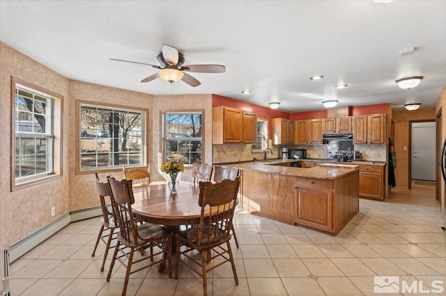 dining area with ceiling fan, sink, light tile patterned flooring, and a baseboard heating unit