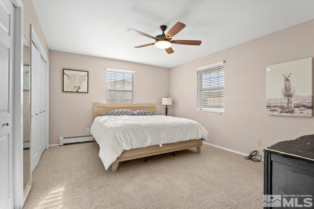 carpeted bedroom featuring ceiling fan, a closet, and a baseboard heating unit