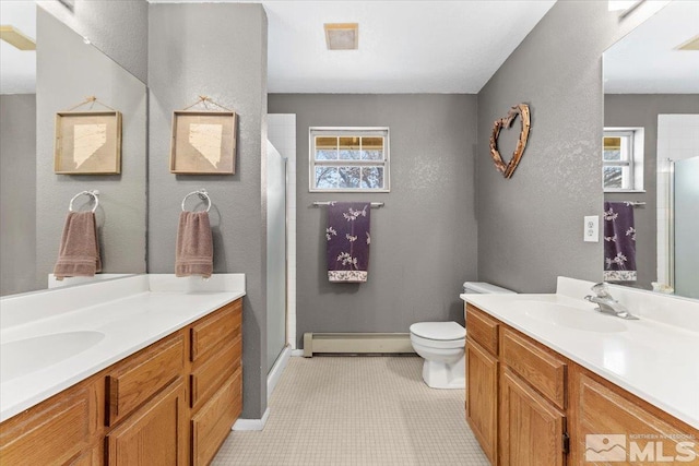 bathroom featuring vanity, a wealth of natural light, and a baseboard heating unit