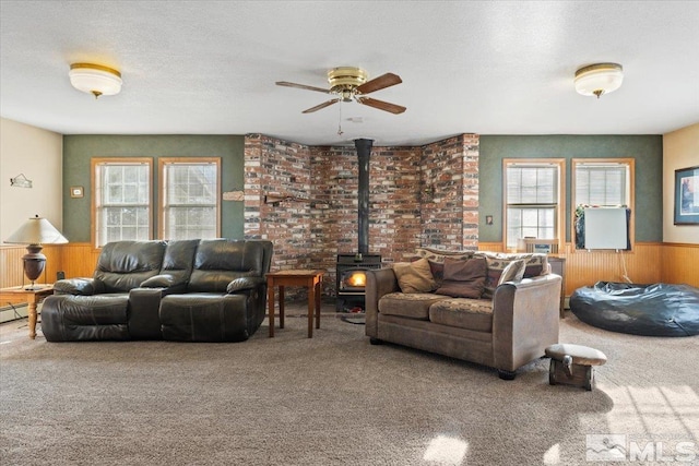 living room with carpet flooring, a wood stove, plenty of natural light, and wood walls