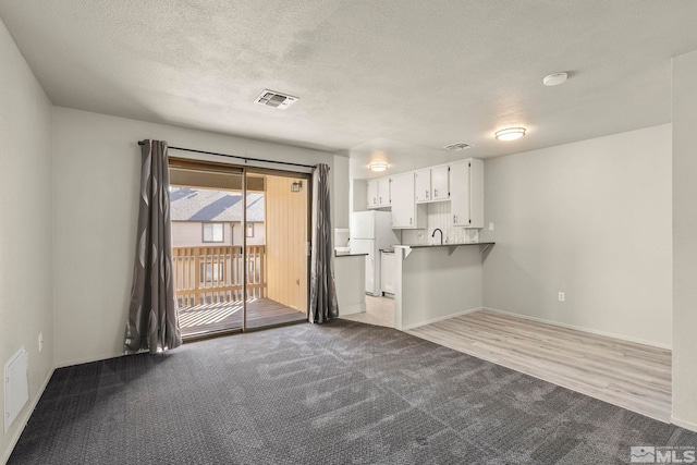 interior space with a textured ceiling, light hardwood / wood-style floors, and sink