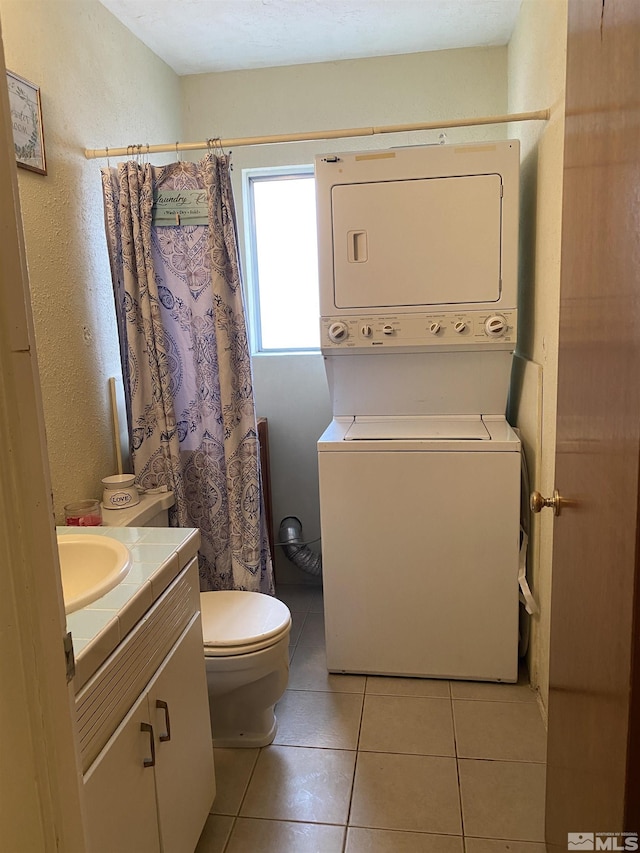 bathroom featuring a shower with curtain, tile patterned flooring, stacked washer / drying machine, toilet, and vanity