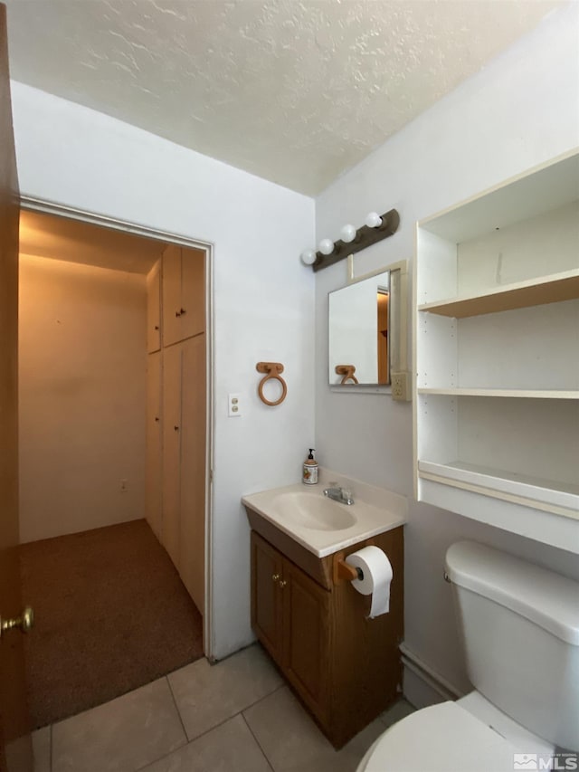 bathroom featuring tile patterned flooring, vanity, a textured ceiling, and toilet