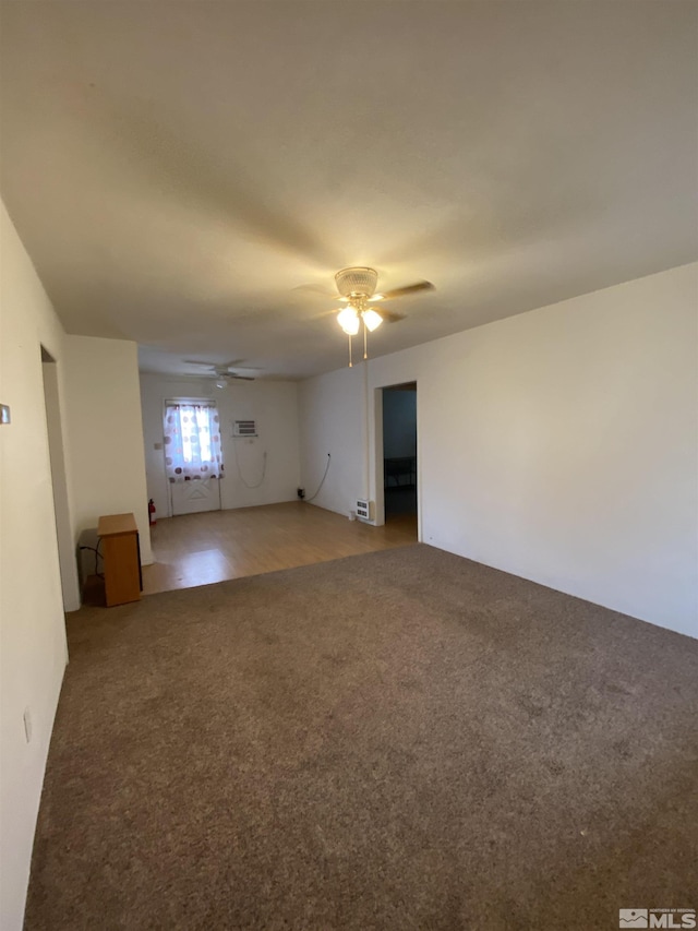 empty room with carpet flooring, a wall mounted AC, and ceiling fan