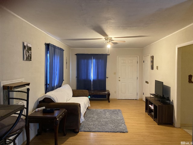 living room with ceiling fan, crown molding, and light hardwood / wood-style flooring