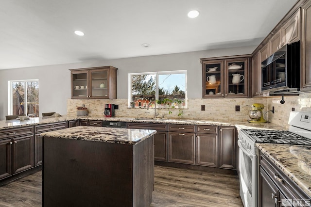 kitchen featuring white range with gas stovetop, dark hardwood / wood-style flooring, light stone countertops, and sink