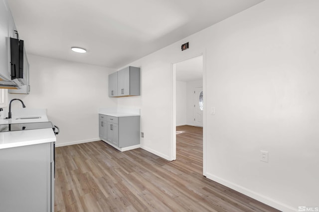 kitchen featuring light wood-type flooring, gray cabinets, and sink