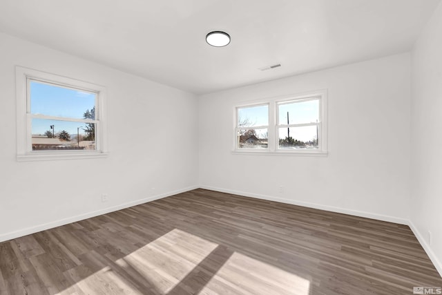 unfurnished room with dark wood-type flooring and a wealth of natural light