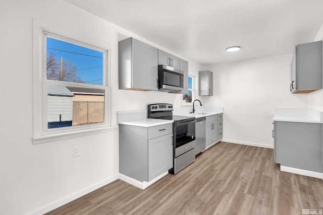 kitchen with gray cabinetry, plenty of natural light, light wood-type flooring, and stainless steel appliances