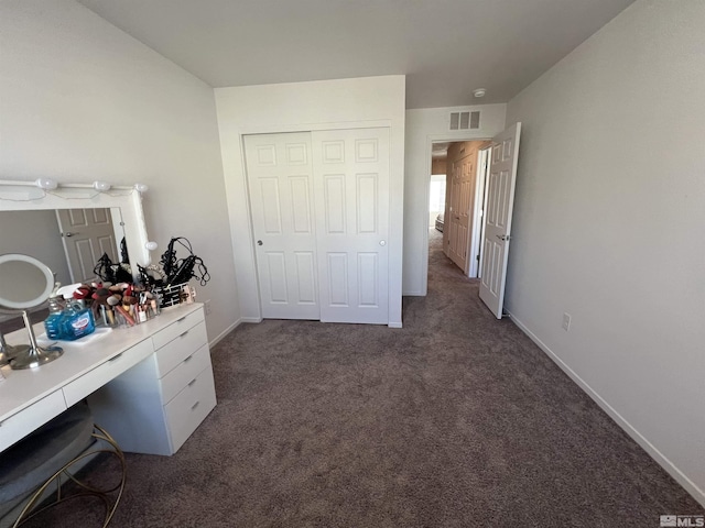 unfurnished bedroom featuring dark carpet and a closet