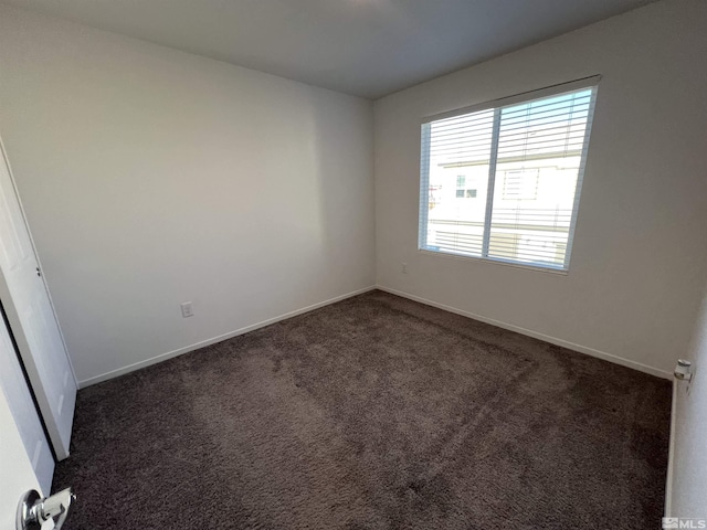 spare room featuring dark carpet