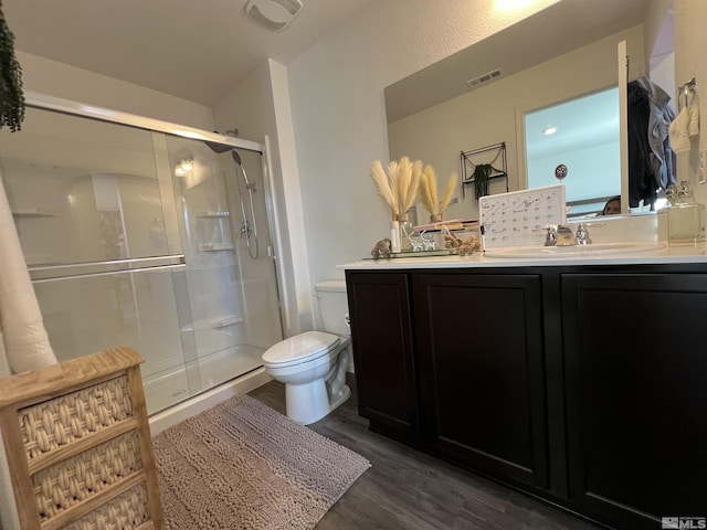 bathroom featuring hardwood / wood-style floors, vanity, toilet, and a shower with door