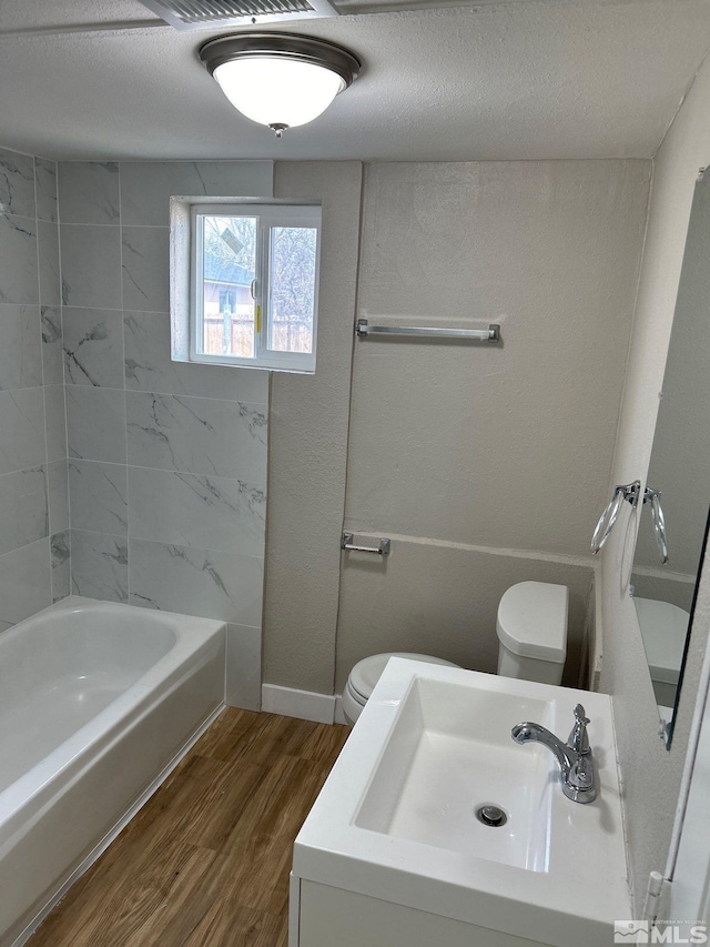 full bathroom featuring hardwood / wood-style floors, toilet, sink, and a textured ceiling