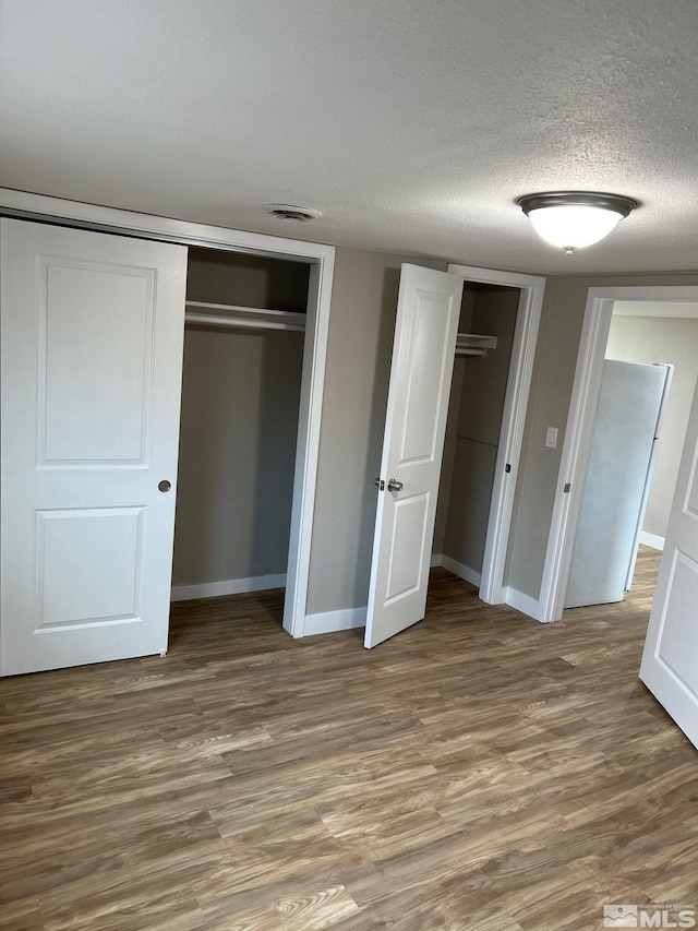 unfurnished bedroom featuring dark wood-type flooring and a textured ceiling