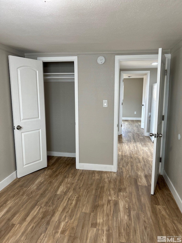 unfurnished bedroom featuring dark hardwood / wood-style flooring, a textured ceiling, and a closet