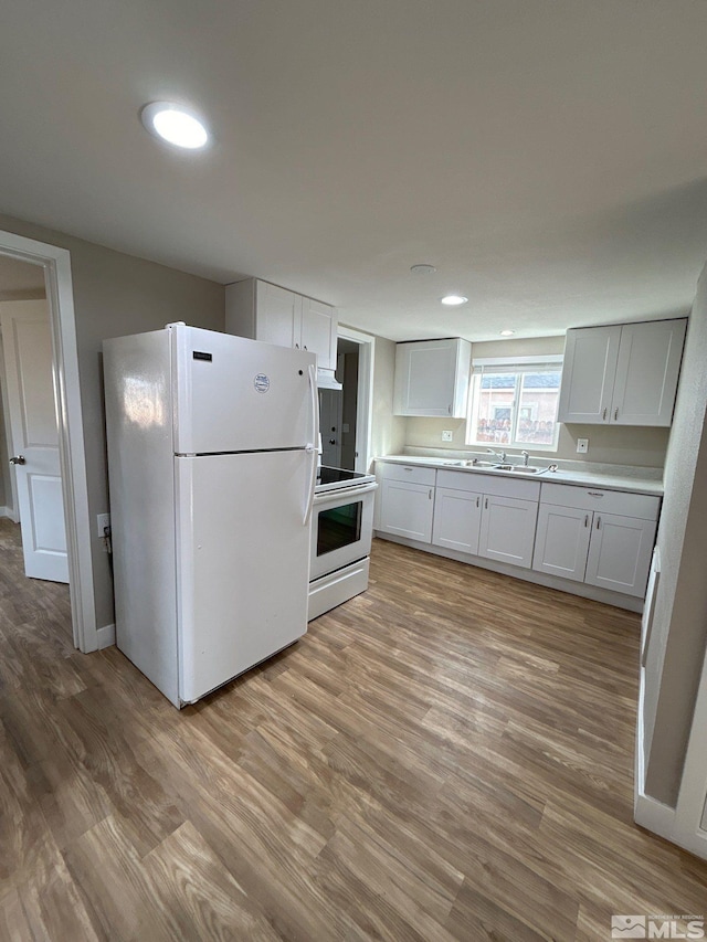 kitchen with white refrigerator, light wood-type flooring, range, and white cabinetry