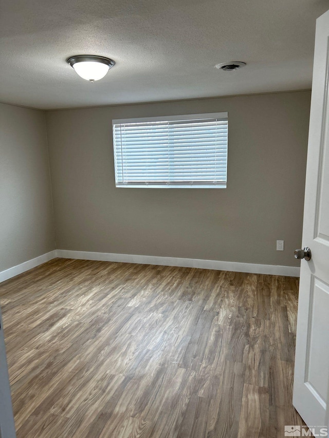 empty room with hardwood / wood-style floors and a textured ceiling