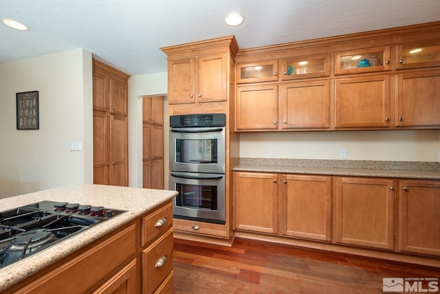 kitchen with dark wood-type flooring, stainless steel double oven, and gas cooktop