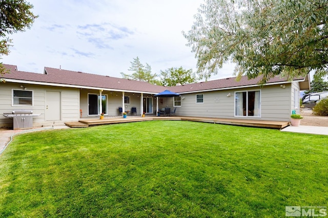 rear view of property with a yard and a wooden deck