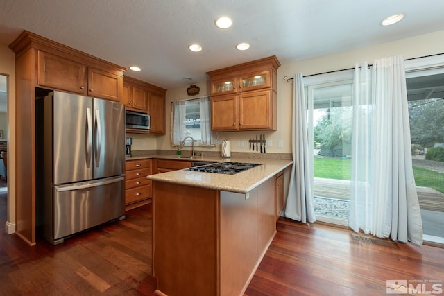 kitchen featuring kitchen peninsula, dark hardwood / wood-style flooring, a breakfast bar, and appliances with stainless steel finishes