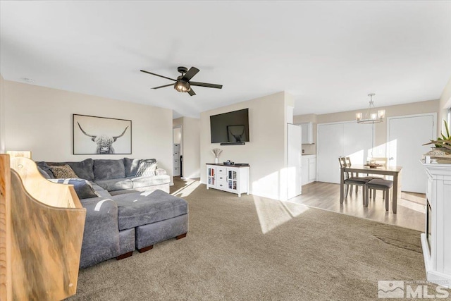 living room with ceiling fan with notable chandelier and carpet floors