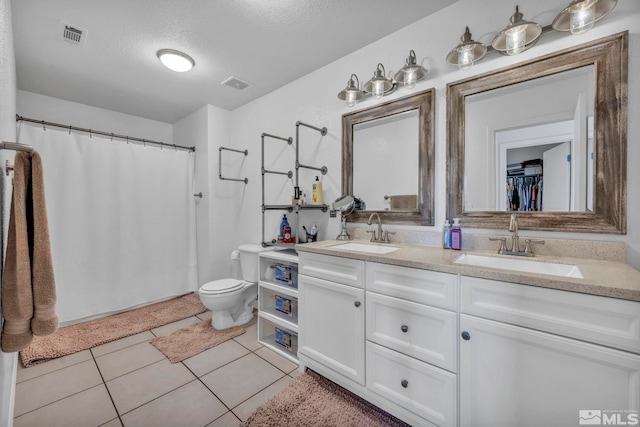 bathroom featuring tile patterned floors, vanity, toilet, and a textured ceiling