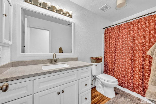 bathroom with vanity, toilet, wood-type flooring, and a textured ceiling