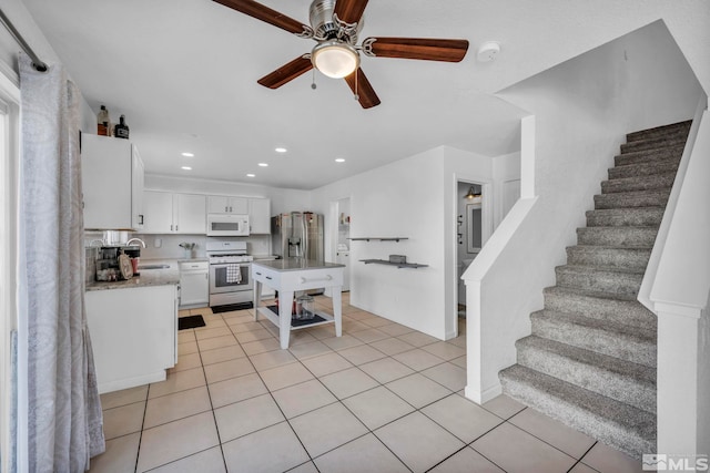 kitchen featuring white appliances, ceiling fan, sink, white cabinets, and light tile patterned flooring